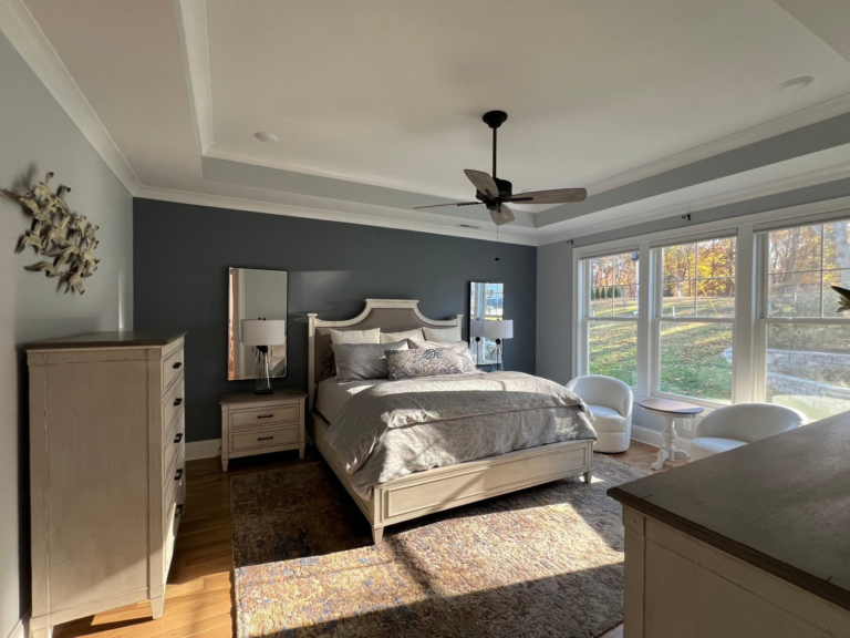Primary bedroom with a deep navy accent wall and white tray ceiling