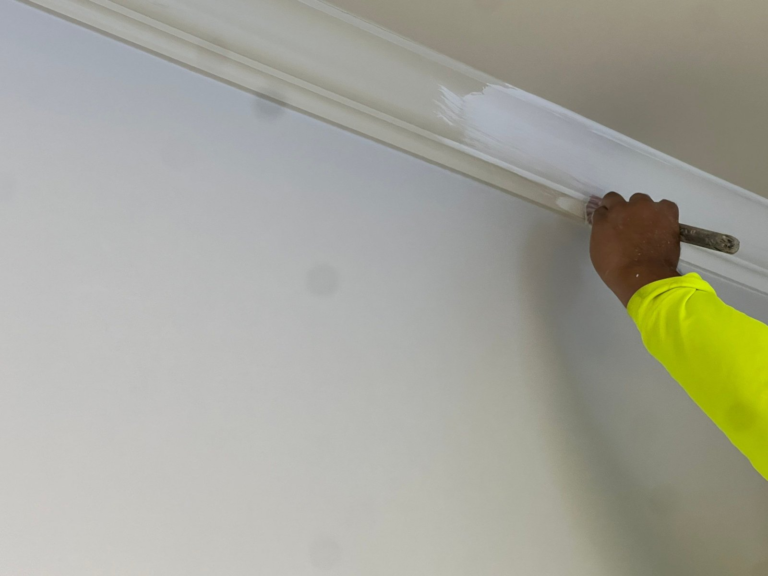 Painter cutting in crown molding by hand during a commercial office repaint